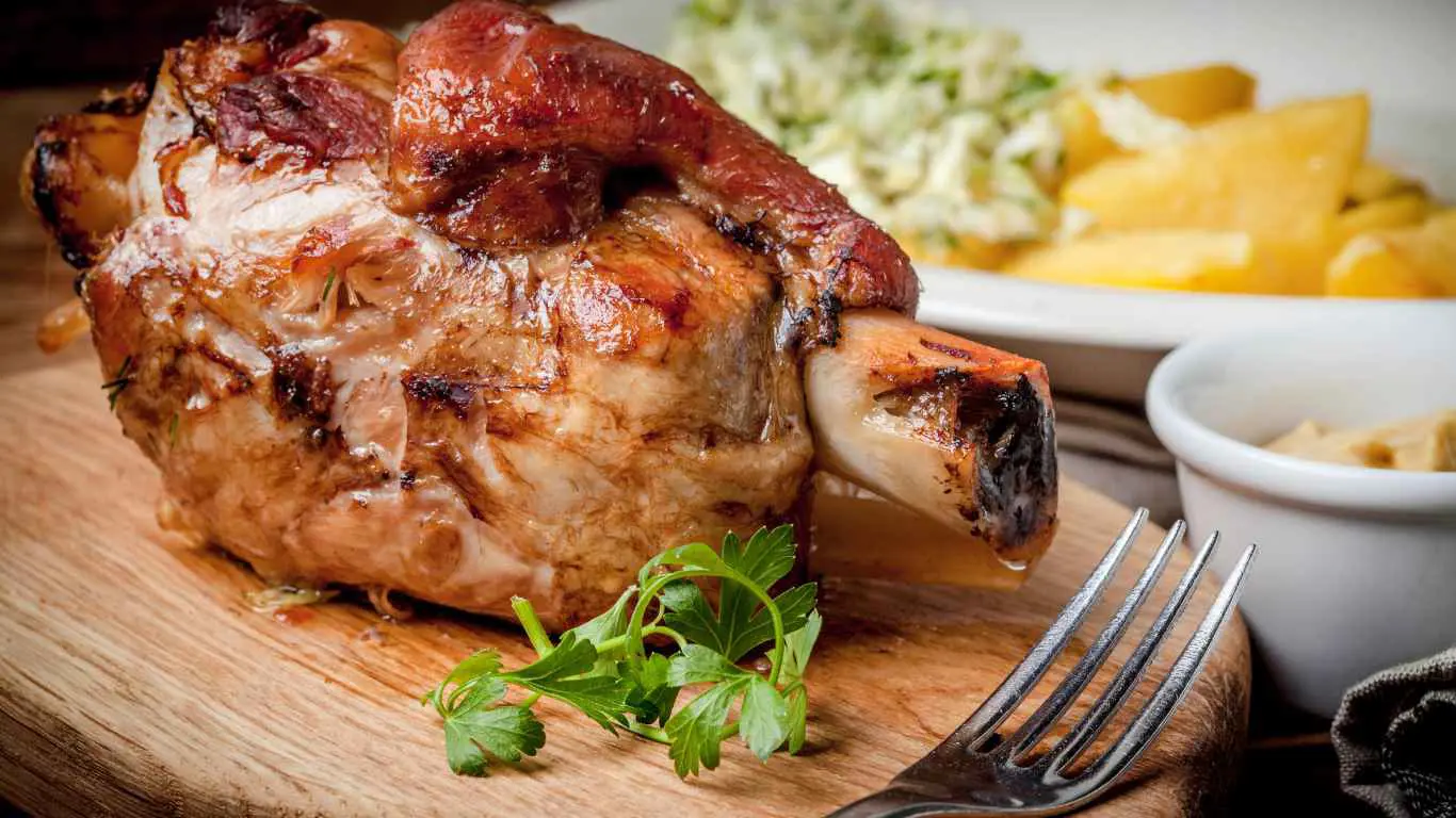 Traditionell servierte Schweinshaxe mit knuspriger Kruste und Beilagen